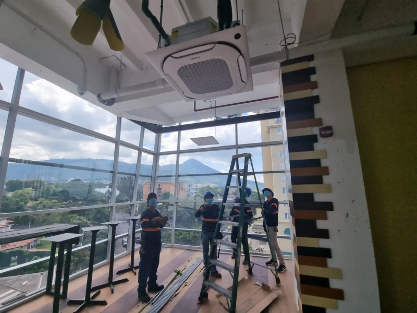 Cuadrilla de Aire Plus instalando una unidad cassette en una terraza con vista a la ciudad