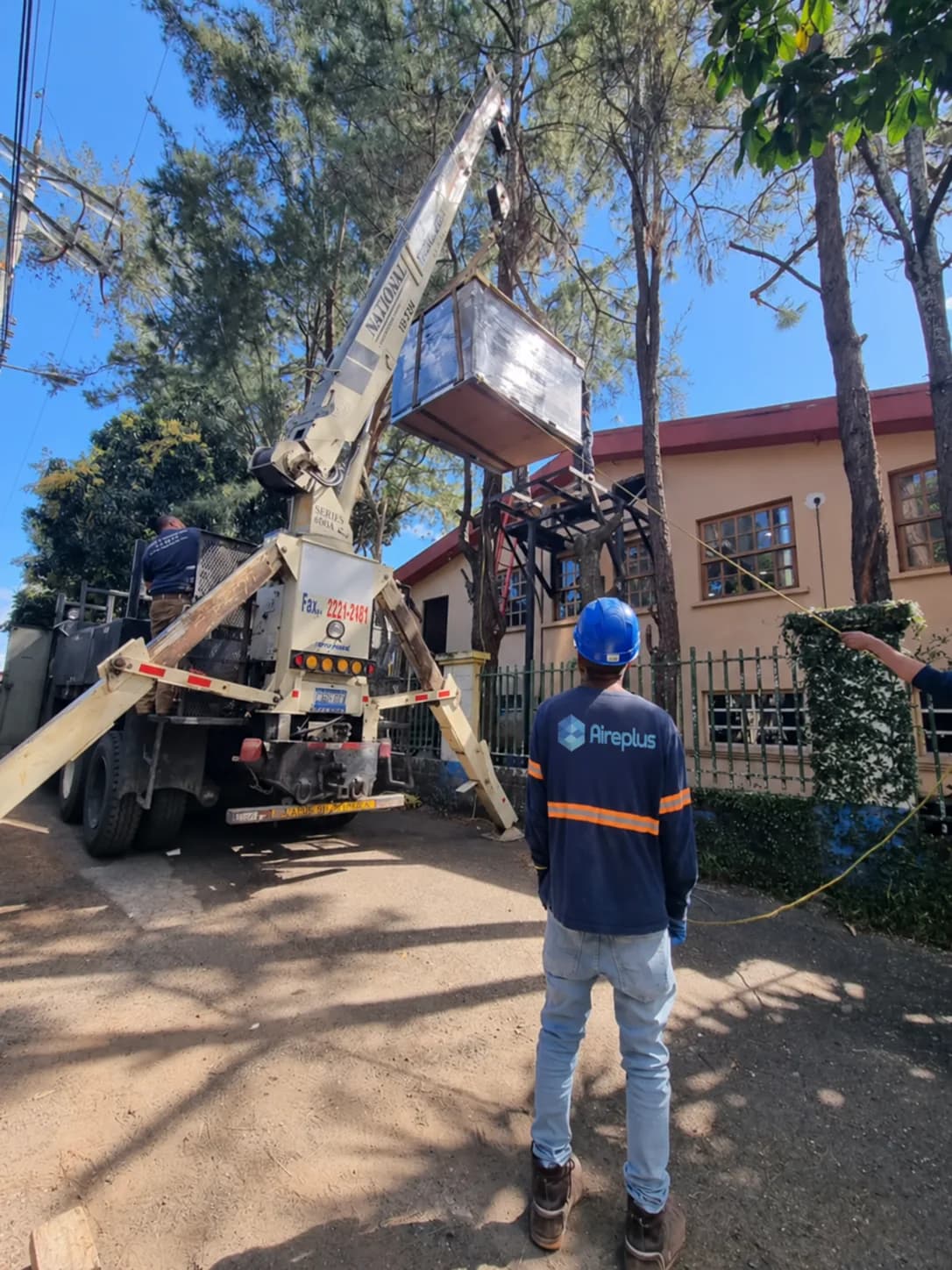 Técnico de Aire Plus supervisando el montaje de un condensador con grúa